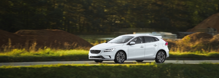 Een witte auto wat aan het rijden is in een beboste omgeving