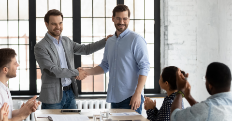 Prinsjesdag werkgevers; werkgever geeft staand een personeelslid een hand tijdens een vergadering met collega's