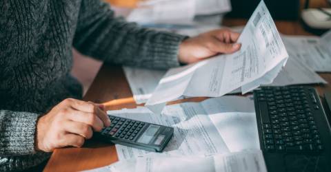 Een man achter een bureau met facturen op zijn bureau 